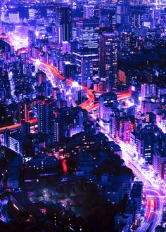 an aerial view of a city at night with neon lights on the buildings and streets