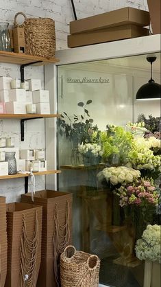 flowers are displayed in the window of a flower shop with baskets and boxes on shelves