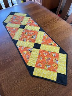 an orange and black table runner sitting on top of a wooden table