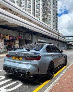 a silver car is parked on the side of the road in front of tall buildings