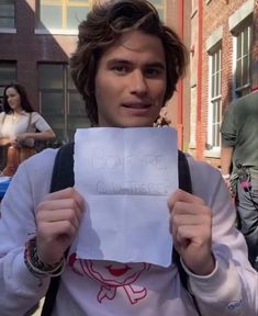 a man holding up a piece of paper with the words bonmpe college written on it