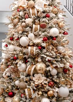 a white christmas tree with gold and red ornaments