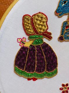 two embroidery designs on a white cloth with gold trimmings and colorful thread work