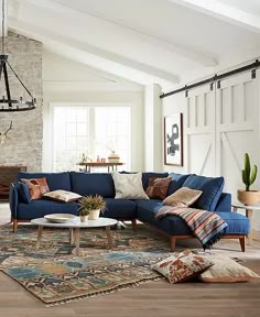 a living room with blue couches and rugs on the floor, windows in the background