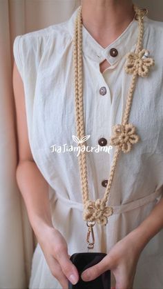 a woman wearing a white shirt holding a black purse and some beads on her necklace