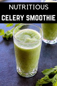 two glasses filled with green smoothie on top of a blue table next to leaves