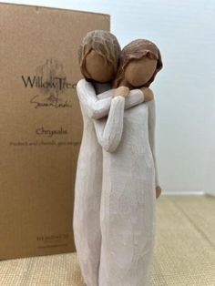 a figurine of two people hugging each other in front of a cardboard box