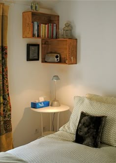 a bedroom with a bed, night stand and bookshelf in the corner on the wall