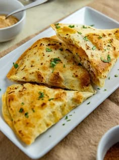 two quesadillas on a plate with dipping sauce