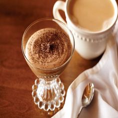 there is a cup of hot chocolate next to a spoon and napkin on the table