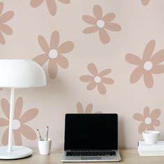 a laptop computer sitting on top of a wooden desk next to a lamp and flower wallpaper