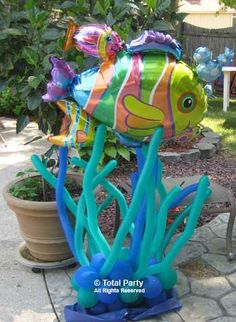 an inflatable clown fish sitting on top of some blue seaweed next to a potted plant