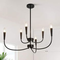 a black chandelier with five lights hanging from the ceiling in a white room