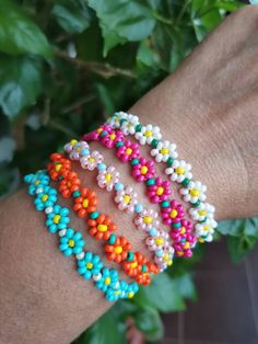 a person's arm with several bracelets on top of it and green leaves in the background