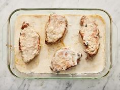 four pieces of meat covered in gravy on top of a glass baking dish