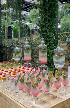 a table topped with lots of wine glasses filled with pink liquid and covered in flowers