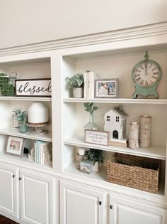 a white bookcase with many items on top of it and a clock in the background