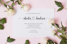 the wedding stationery is laid out on top of pink paper with white roses and greenery