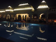 an outdoor swimming pool at night with lights on