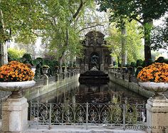 an outdoor fountain surrounded by trees and flowers