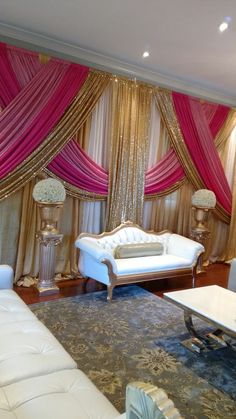 a living room with couches, chairs and curtains on the windowsills is decorated in pink and gold