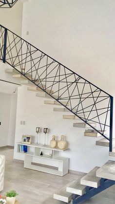 a living room with white furniture and a metal stair case on the wall next to a coffee table