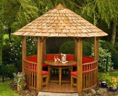 a wooden gazebo sitting on top of a lush green field