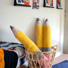 two yellow pencils are in a basket on the floor next to some pictures and a blue rug