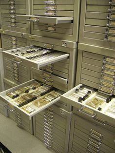 the drawers are full of files and folders in an office area with metal cabinets