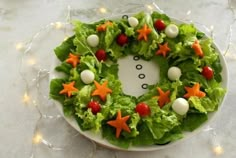 a christmas wreath made out of lettuce and carrots on a white plate