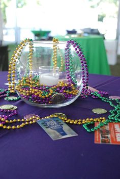 a table topped with a glass bowl filled with beads and other items on top of it