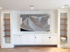 a living room with white walls and shelving units covered in a sheeted cloth