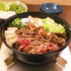 a bowl filled with meat and vegetables on top of a table