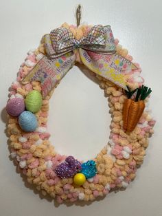 a knitted easter wreath hanging on the wall with an egg, carrot and candy