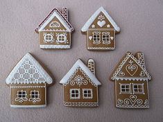 four decorated gingerbread houses are shown on a pink surface with white trimmings