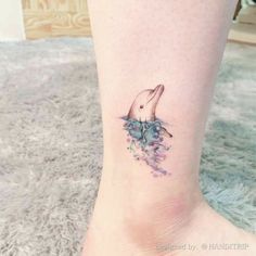 a woman's foot with a small tattoo of a dolphin swimming in the ocean