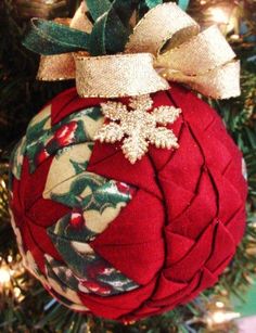 an ornament hanging from a christmas tree decorated with red and green fabric, gold bows and snowflakes