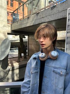 a young man wearing headphones standing in front of a building