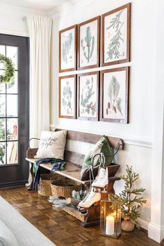 a wooden bench sitting in the middle of a living room next to a window with pictures on it