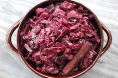 a bowl filled with red cabbage next to a wooden spoon