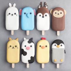 an assortment of ice cream pops decorated like animals and cats, with faces on them