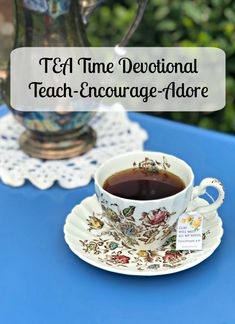 a tea cup and saucer on a blue table with the words t & f time devotional teach - encourage - adore