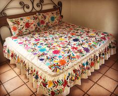 a bed with a colorful quilt on top of it in a room next to a wall