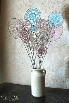 a vase filled with lots of blue and pink balls on top of a table next to a wall