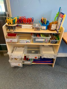 a shelf filled with lots of school supplies on top of a blue carpeted floor