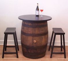 a table with two stools and a wine bottle on it next to a wooden barrel