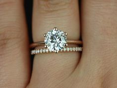 a woman's hand with a diamond ring on top of her wedding band and an engagement ring in the middle