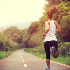 a woman running down the road with trees in the background