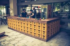 two people sitting at a bar in front of a building with yellow boxes on the counter