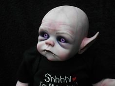 a baby doll with white hair and purple eyes is wearing a black shirt that says, shhn i'm my mom